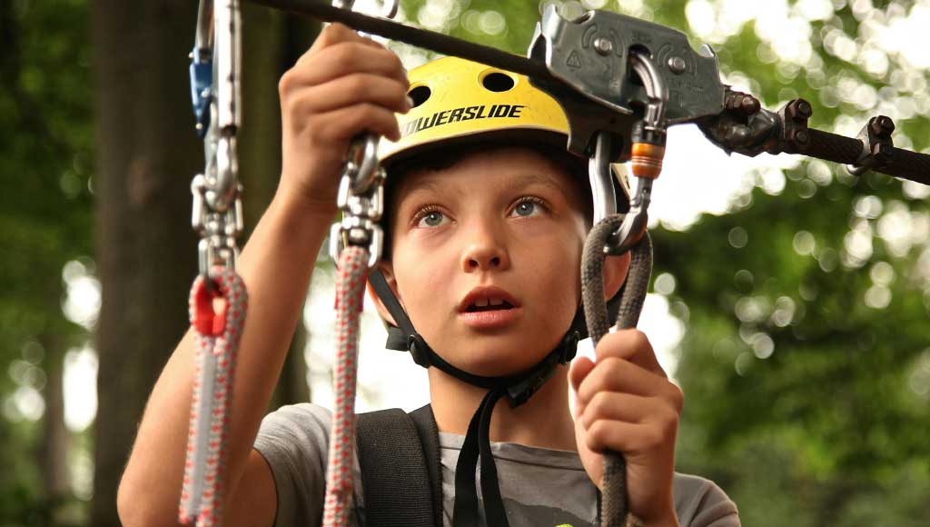 A boy fastening a zip line - Camp Adventures - camping in uae